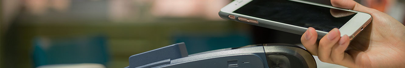 A person holding a smart phone close to a card reader machine at checkout