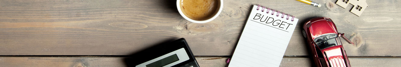 House, Car, Note Pad for Budget, Calculator and Coffee on a table