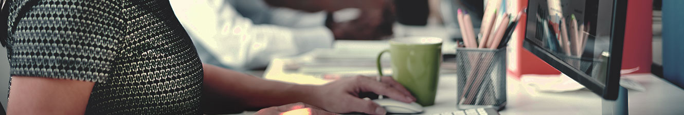 A woman siting at a desk in front of a computer holding the mouse